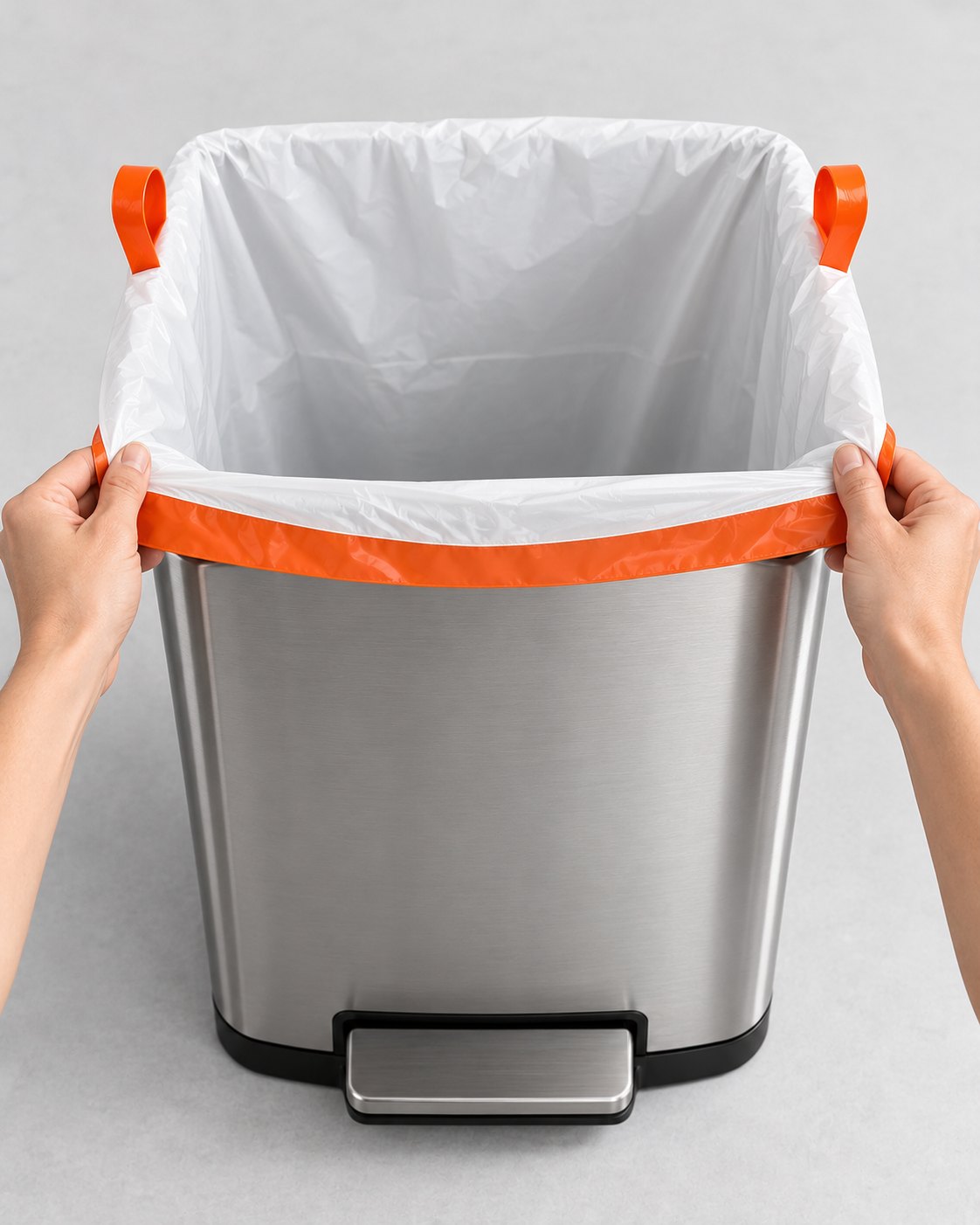 Hands stretching the elastic hem of a BinDone liner over a stainless can rim
